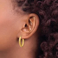 A person wearing gold hoop earrings is shown in profile from the shoulder up, with textured dark hair visible against a warm brown background.