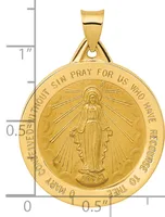 Gold medallion pendant featuring a central figure with radiating lines, surrounded by text around the rim, shown next to a ruler indicating approximately one inch in height.