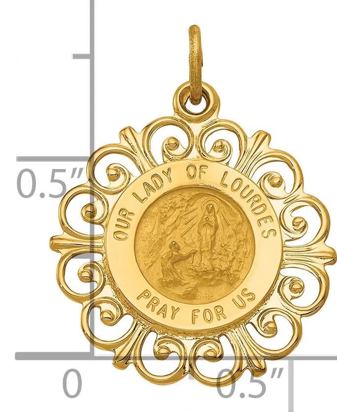 Gold-toned ornate religious medal pendant with scrolling filigree border and central circular disc engraved with a figure, shown next to a ruler indicating approximately one inch in width.