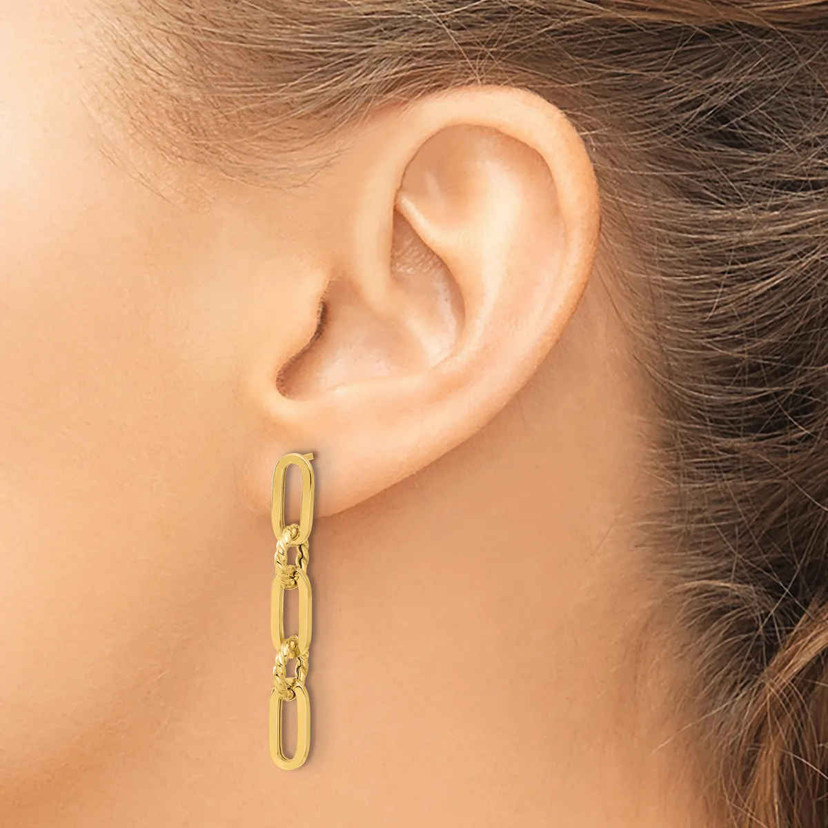 A person wearing a long gold-toned chain link earring that hangs from the earlobe, shown from a side profile view.