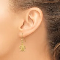 A woman wearing a gold turtle-shaped dangle earring on a hook, shown from the side view of her ear and neck.