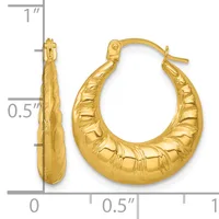 Pair of gold-colored textured hoop earrings with a tapered oval shape, displayed with a measurement scale showing approximately one inch in height.