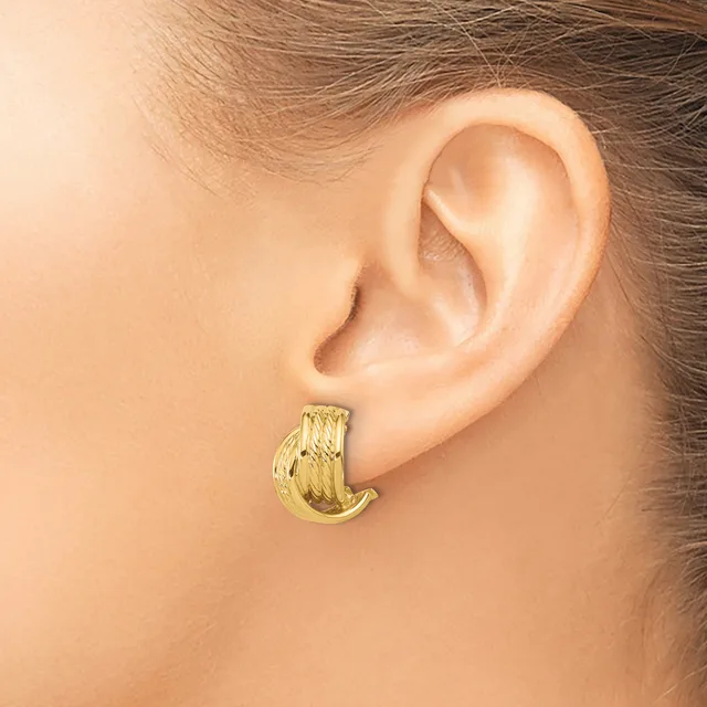 A gold textured chunky hoop earring worn on the earlobe of a person shown in profile from the side of their head and neck.