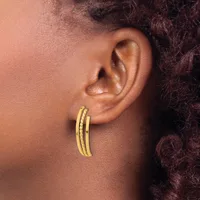 A person wearing a pair of gold hoop earrings with a textured surface, shown from the side profile of their ear and neck.