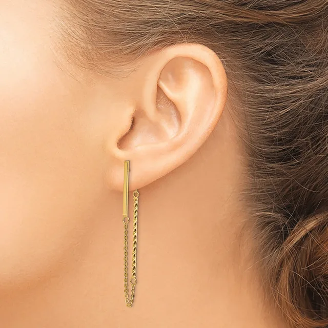 A woman wearing a long gold chain threader earring that hangs through her pierced earlobe.