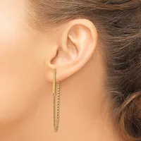A woman wearing a long gold chain threader earring that hangs through her pierced earlobe.