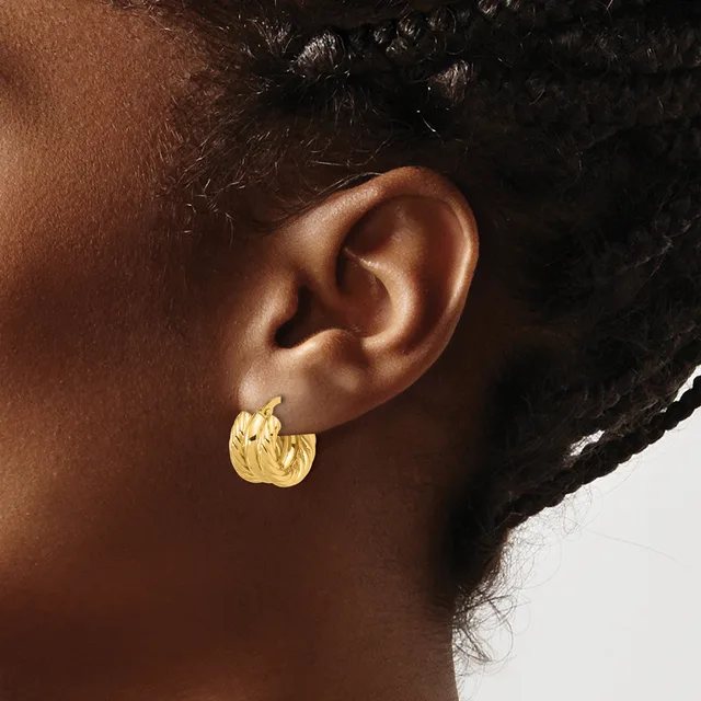 A person wearing a textured gold hoop earring with a hammered finish, shown in profile against a neutral background.