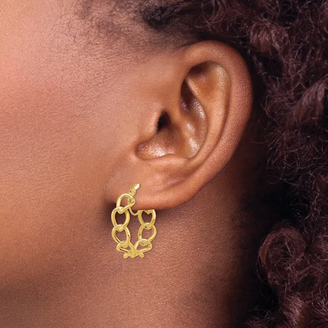 A gold heart-shaped link earring with a spring ring closure worn on a person's earlobe.