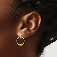 Gold-toned drop earring with a rectangular post and circular hoop adorned with small beaded details, worn on a person's earlobe.
