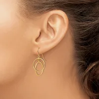 A person wearing gold-toned interlocking oval hoop earrings on fish hook ear wires, shown from the side profile of their ear and neck.