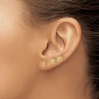 A person's ear with three small gold stud earrings: a cross, a crescent moon, and a crown.