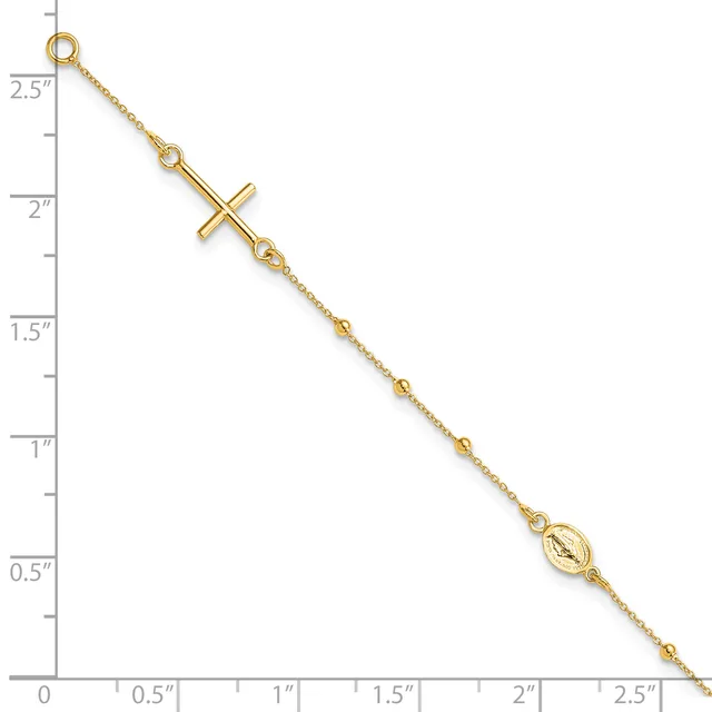 A gold-toned chain bracelet with a sideways cross pendant and a small oval medallion charm, displayed against a ruler showing it measures approximately 2.5 inches in length.