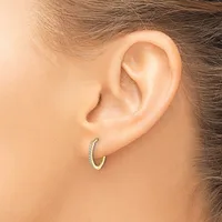 A gold hoop earring with diamond accents worn in a woman's earlobe, shown from a side view.