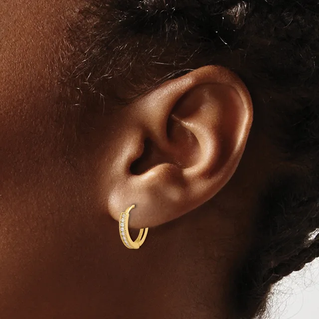 A small textured gold hoop earring worn on the earlobe of a person with brown skin and dark hair.