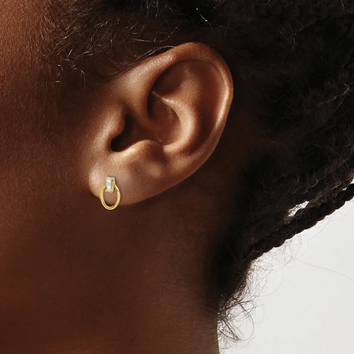 Close-up of a person's ear wearing a small gold hoop earring, showing the earlobe and surrounding skin.