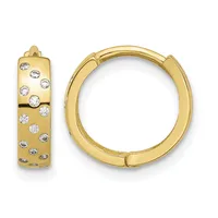 A pair of gold huggie hoop earrings set with round diamonds scattered across the front surface, shown from front and side views.