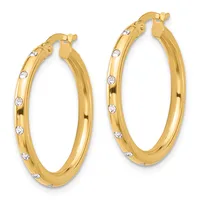 A pair of gold hoop earrings with round diamond accents spaced along the outer surface, shown from the front.