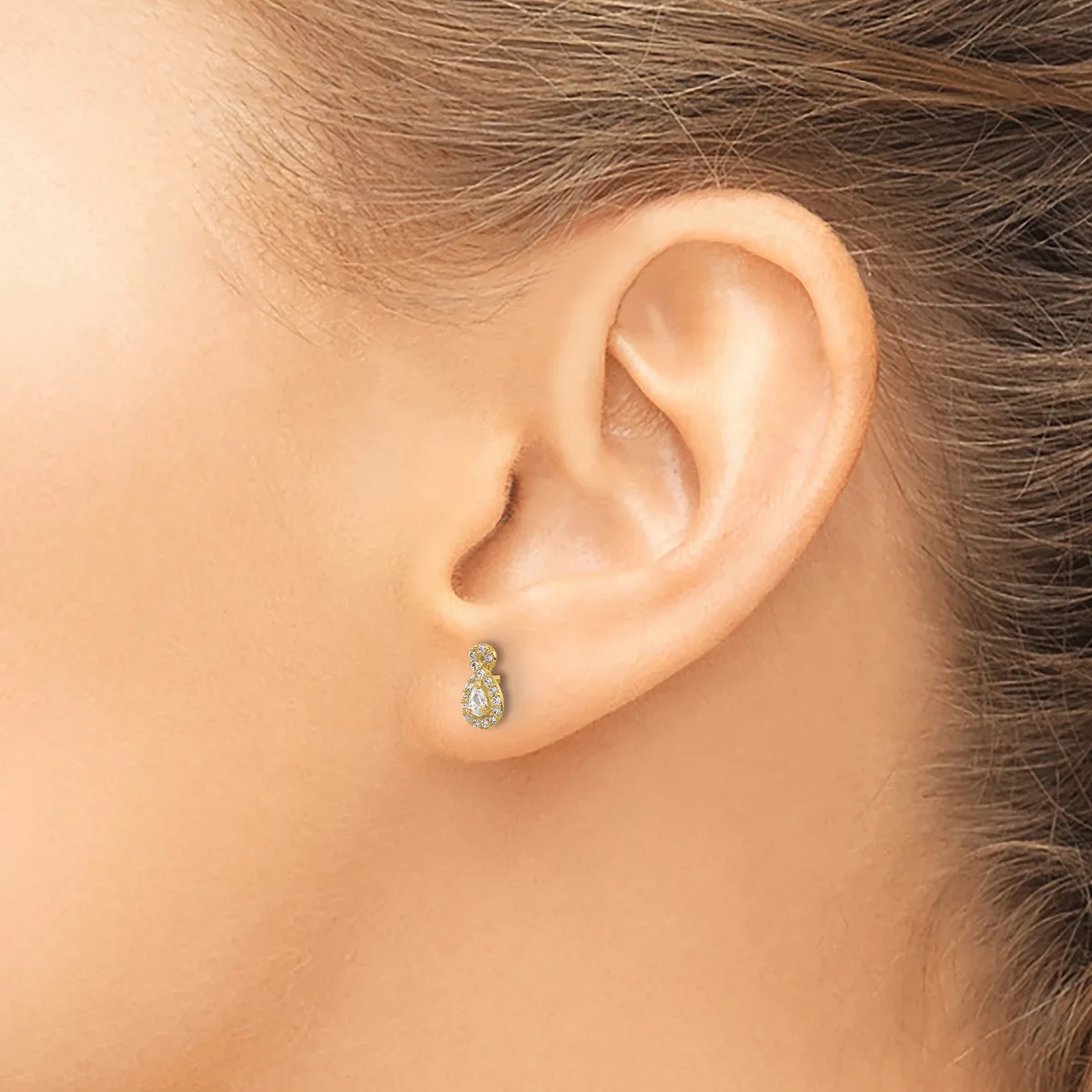 Close-up side view of a person's ear wearing a small teardrop-shaped stud earring with a pear-cut gemstone and diamond accents.