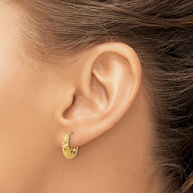A person wearing a gold textured hoop earring in their pierced earlobe, shown in profile view against their shoulder and neck.