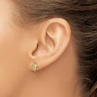 A small gold turtle-shaped stud earring with gemstone accents is worn in the earlobe of a person with brown hair.