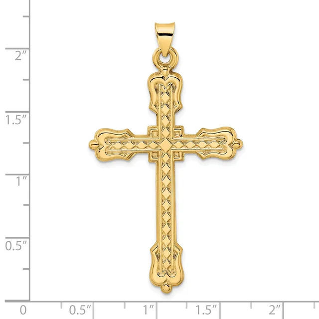 A gold cross pendant with decorative lattice pattern and ornate flared ends, shown against a measurement scale.