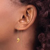 A person wearing gold threader earrings with small pendant charms hanging from thin chains against their ear.