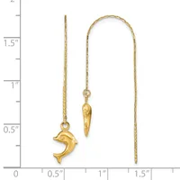 Two gold threader earrings displayed against a measurement scale: one featuring a dolphin charm and one with an elongated cone-shaped pendant.