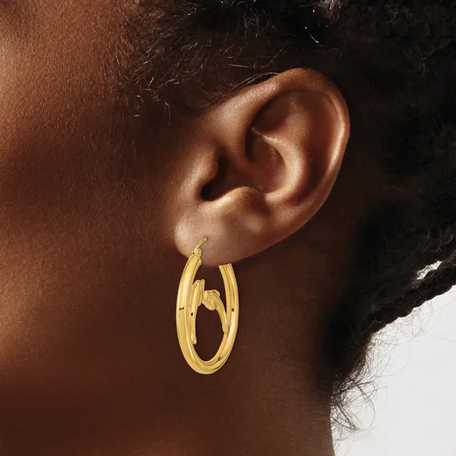 A person wearing double gold hoop earrings with a grooved texture, shown from the side profile of their ear and neck.