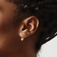 A person wearing a small gold hoop earring with a textured charm hanging from it, shown from the side view of their ear and neck.