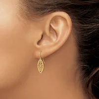 A woman wearing a gold filigree leaf-shaped dangle earring on a hook post, shown from the side profile of her ear and neck.
