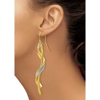 A woman wearing long twisted gold and silver two-tone drop earrings with a textured surface, shown from the side profile.