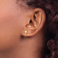Close-up side view of a person's ear wearing a small gold heart-shaped stud earring.