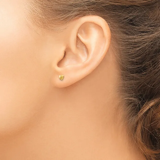 A person wearing a small yellow-green gemstone stud earring in their pierced earlobe, shown from the side profile.