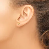 A person wearing a small yellow-green gemstone stud earring in their pierced earlobe, shown from the side profile.