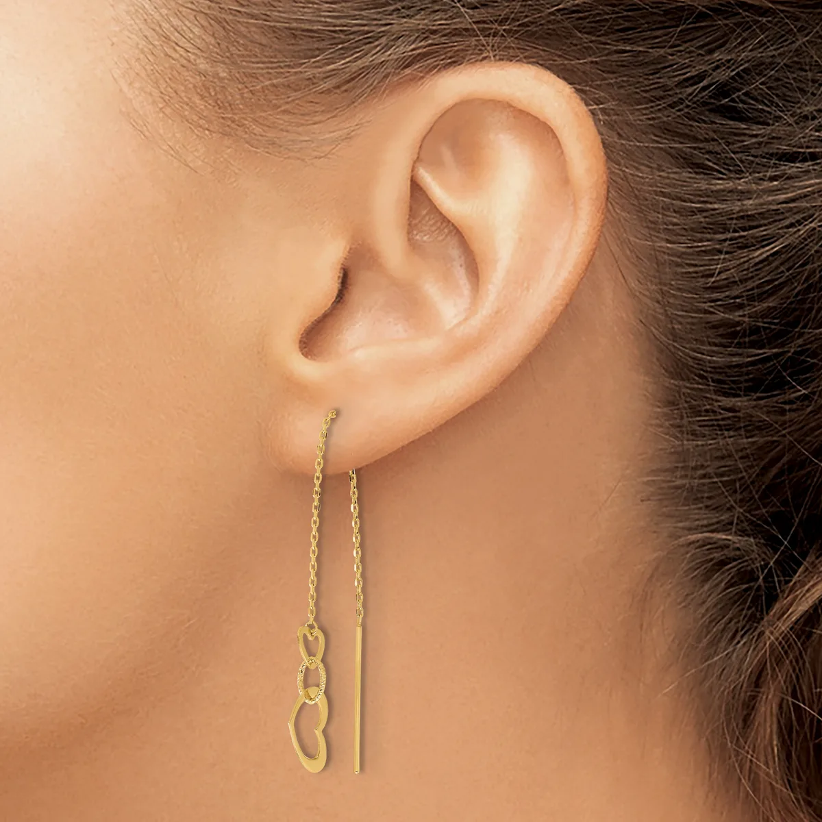A person wearing two gold chain threader earrings, one with small linked loops and one plain, hanging from pierced ears.