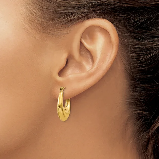 A person wearing a pair of polished gold hoop earrings, shown from the side with dark hair pulled back.