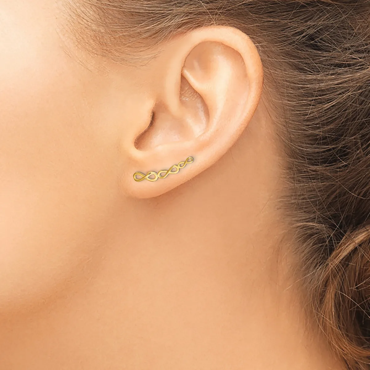 A gold curved bar earring with a series of small linked oval shapes runs horizontally across the earlobe of a person shown in profile.