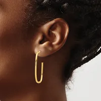 A woman wearing a pair of polished gold hoop earrings with a rounded rectangular shape, shown from the side profile view.