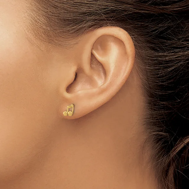 Close-up side view of a person's ear wearing small gold stud earrings with a decorative curved design.