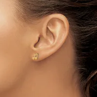 Close-up side view of a person's ear wearing small gold stud earrings with a decorative curved design.