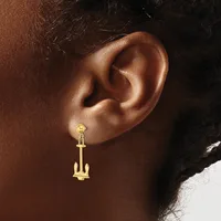Gold anchor-shaped drop earring hanging from an earlobe, shown in profile view against a person's neck and shoulder.