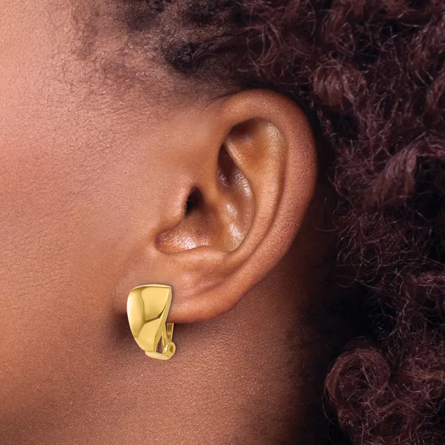 A person wearing a polished gold-toned chunky curved rectangular earring in their earlobe, shown from the side profile view.