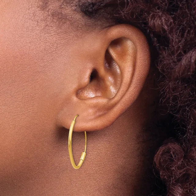 A person wearing a gold hoop earring in their earlobe, shown in profile against their neck and shoulder.