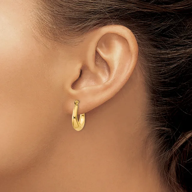 A person wearing a gold hoop earring in their earlobe, shown in a close-up side view of their ear and neck.