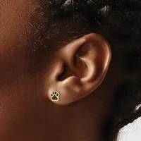A gold paw print stud earring worn on the earlobe of a person with medium brown skin tone and dark hair.
