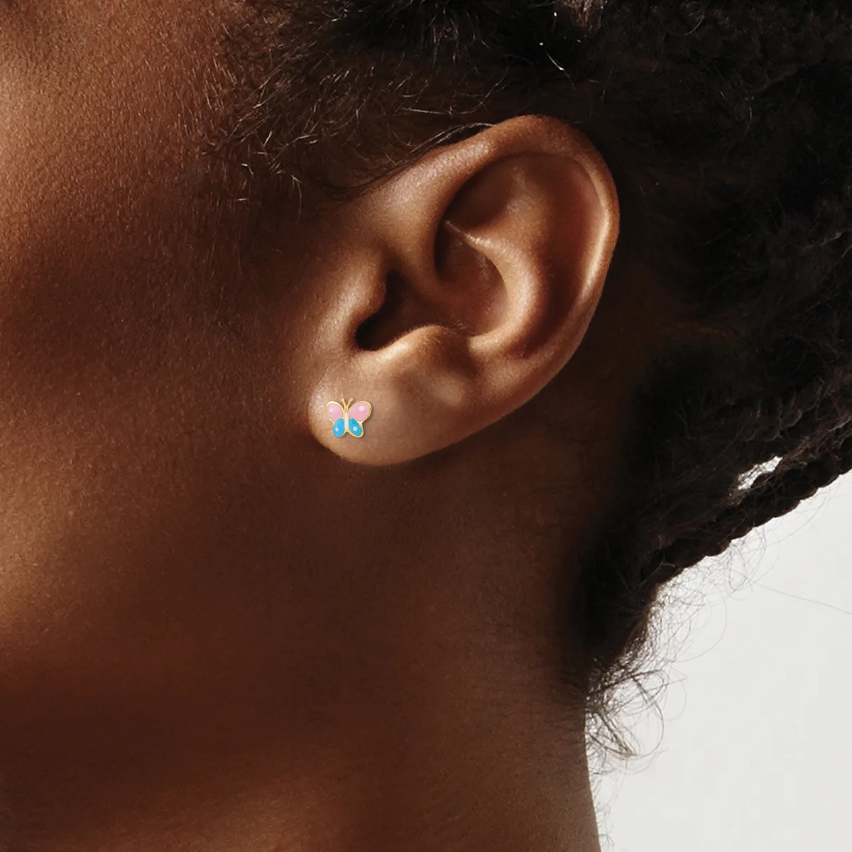 A person wearing a small blue butterfly-shaped earring with a post fastening, shown in profile against a neutral background.