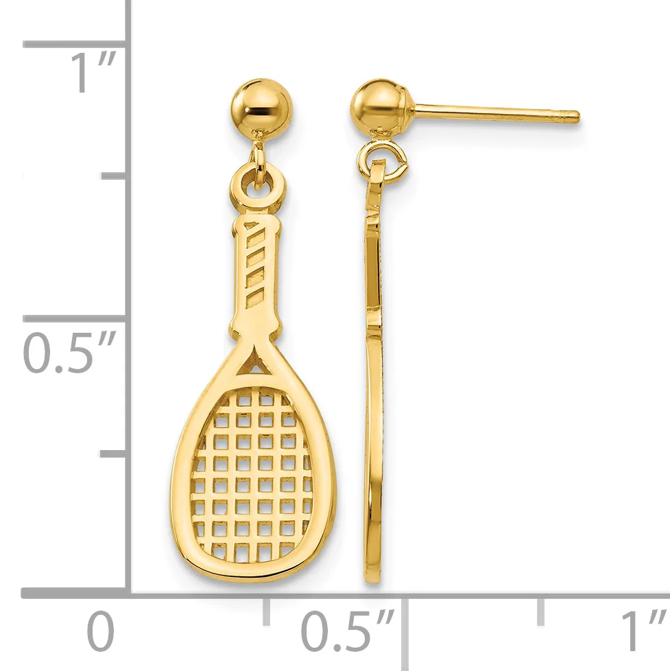 Pair of gold-colored tennis racket dangle earrings with ball studs, shown next to a ruler measuring approximately one inch in length.