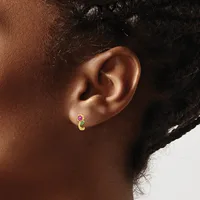 A close-up side view of a person's ear wearing a small gold hoop earring with a pink gemstone at the top.