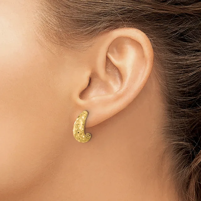 A woman wearing a textured gold teardrop-shaped hoop earring in her pierced earlobe, shown in profile against a neutral background.