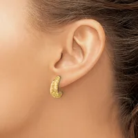 A woman wearing a textured gold teardrop-shaped hoop earring in her pierced earlobe, shown in profile against a neutral background.